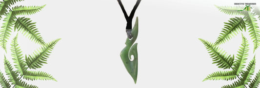 Close-up of a beautiful greenstone necklace, featuring a finely carved pendant made from pounamu, surrounded by fern leaves in a minimalist design.