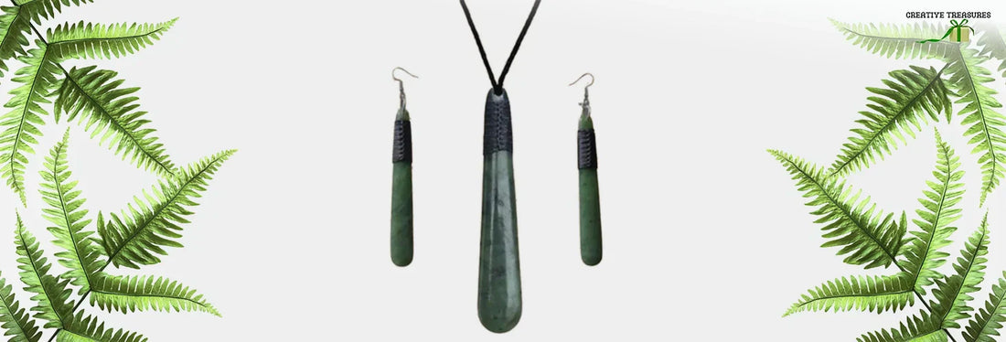 Greenstone drop pendant and matching earrings set framed by fern fronds, representing traditional Māori symbols and cultural storytelling